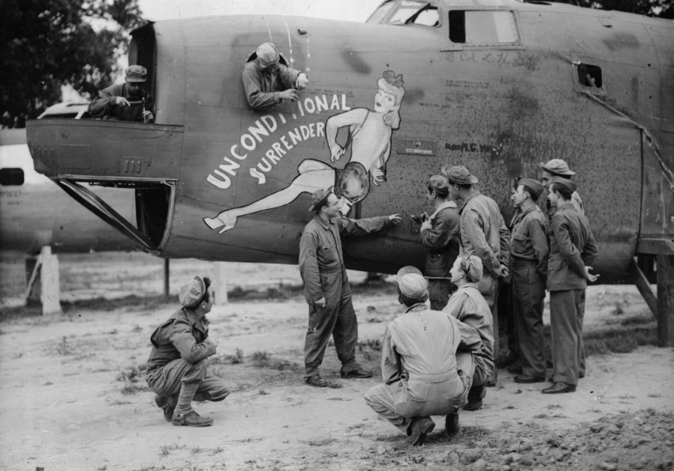 Airmen of the 491st Bomb Group admire the nose art of a B-24 Liberator (serial number 42-110146) nicknamed "Unconditional Surrender".