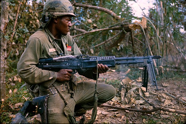 On 8 January 1967, PFC Milton L. Cook (Baltimore, MD) fires his M60 machine gun spraying a tree line. The platoon received sporadic sniper fire from the tree line earlier. PFC Cook was one of many Soldiers from Company C, 1st Battalion, 5th Mechanized Infantry, 25th Infantry Division on a search and destroy mission. The mission was a part of Operation Cedar Falls conducted in and around the Filhol Plantation near Cu Chi, Republic of Vietnam.
