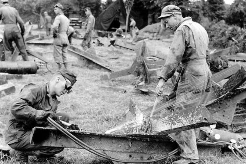 Ordnance Soldiers welding hedgerow cutters, June 1944.